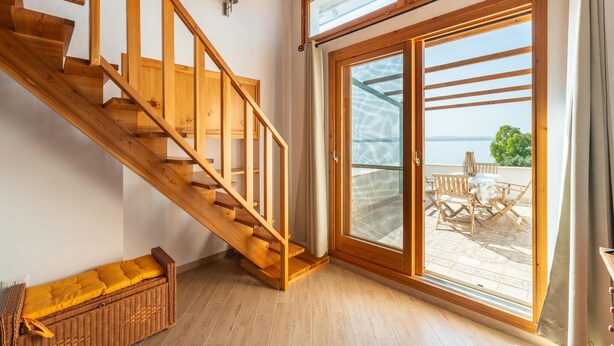 Eine Holztreppe führt zu einem Balkon mit Meerblick.