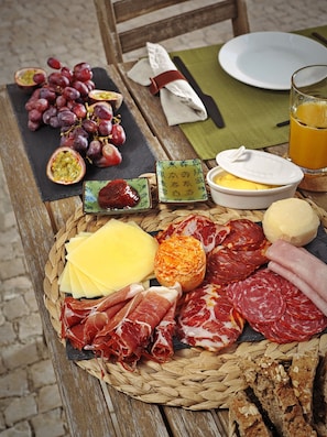 A table with a variety of food items including cheese, cured meats, and fruits. - Lapa 82 Boutique Bed & Breakfast (Lisbon)