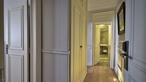 Un pasillo con piso de madera, paredes blancas y una puerta que da a un baño.