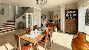 Un'ampia zona giorno con una scala in legno, un tavolo da pranzo con sedie e un grande vaso.