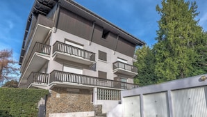 Un edificio a più piani con balconi, facciata in pietra e un garage.