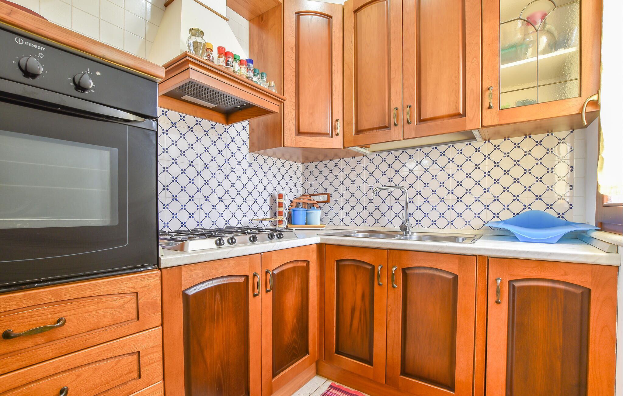 A kitchen with wooden cabinets, a stove, and a tiled backsplash.