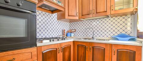 A kitchen with wooden cabinets, a stove, and a tiled backsplash.