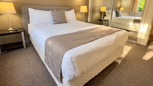 Een hotelkamer met een groot bed, bedlampen, een spiegel en een vloerbedekking.