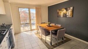 Een moderne keuken met een eethoek, een groot raam en een schuifpui die uitkomt op een terras.