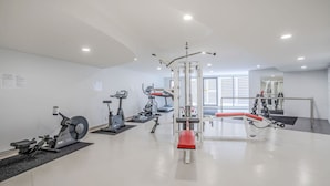 Un gimnasio moderno con varios equipos de ejercicio, incluyendo cintas de correr, una bicicleta estática y máquinas de pesas.