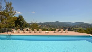 A swimming pool with lounge chairs and tables, surrounded by a fence, with a view of distant mountains. - 1 bedroom pet friendly apartment in Citerna (Citerna)