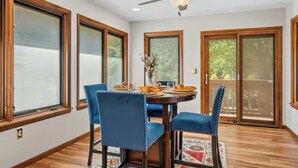 Un coin repas avec une table ronde, des chaises bleues et un ventilateur de plafond.