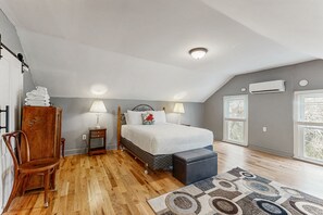 Une chambre à coucher avec un lit, des tables de chevet, une chaise, un tapis et une fenêtre.