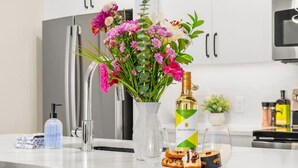 A modern kitchen with white cabinetry, a stainless steel refrigerator, a built-in microwave, and a wooden countertop.