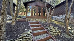 A wooden cabin with a stone pathway leading to it, surrounded by trees. - Lovely 2-Bedroom with Loft Condo at the Base of Snowshoe--a Perfect Getaway! (Snowshoe)