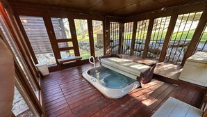 A hot tub in a covered outdoor area with wooden flooring and a view of a grassy landscape. - Lovely 2-Bedroom with Loft Condo at the Base of Snowshoe--a Perfect Getaway! (Snowshoe)
