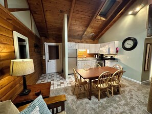 L’intérieur d’un chalet confortable, avec une salle à manger, une cuisine et un plafond en bois.