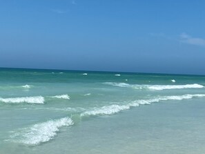 Ein Strand mit klarem türkisblauem Wasser und sanften Wellen.