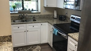 A kitchen with white cabinets, a stainless steel refrigerator, a microwave, and a stove. - 2-bedroom condo in Sarasota 1 1/2 miles from beautiful Siesta Key (Sarasota)