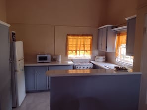 A compact kitchen with a refrigerator, microwave, stove, and sink. - Enjoyable 2-bedroom building with AC in charming Birch Grove (Birch Grove)