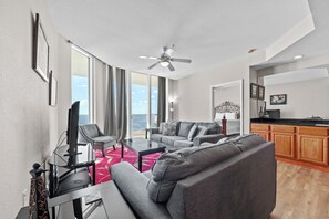 Una sala de estar moderna con un sofá, una mesa de centro y un televisor. Cuenta con un balcón con vistas al mar.