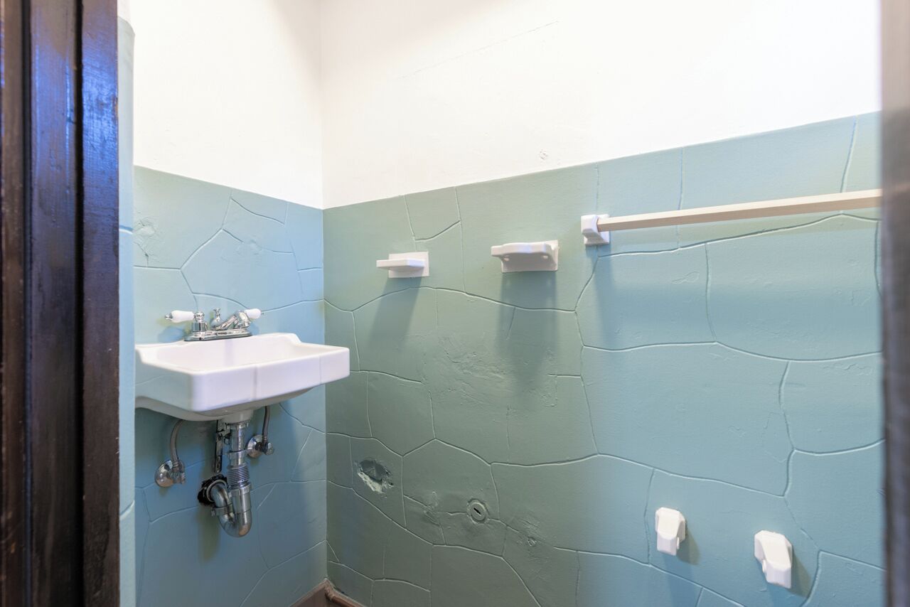 A bathroom with a white sink, a mirror, and a towel rack.