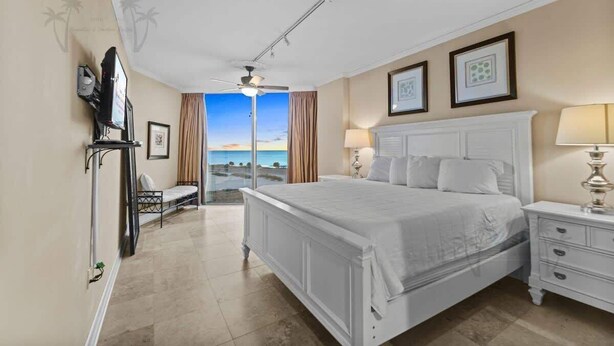 Una camera da letto con un letto grande, un comodino, una sedia, una televisione e vista sull'oceano.