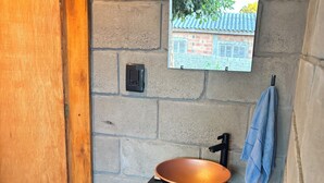 A bathroom with a wooden door, a black sink with a copper bowl, a mirror, and a towel hanging on the wall. - Kiosk with Private Pool (Sapucaia do Sul)