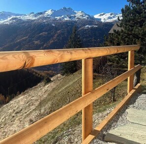 Eine Holzhandläufe mit Blick auf eine gebirgige Landschaft mit schneebedeckten Gipfeln.
