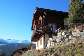 A wooden chalet with a balcony, set against a mountainous backdrop. - Charmant appartement en rez-de-chaletIdéalement situé sur la route du funiculaire, cet appartement e (St-Luc)