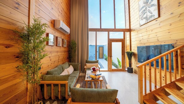 Un interior de madera con un sofá, una mesa y una escalera.