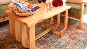Un interior de madera con un sofá, una mesa con aperitivos, bebidas y un ramo de rosas.