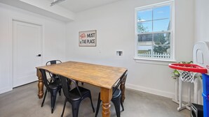 Un comedor con una mesa de madera y sillas negras, un aro de baloncesto y un cartel en la pared.