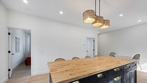 Una cocina moderna con una isla de madera, armarios negros y una lámpara colgante.