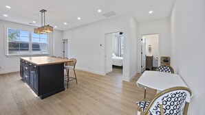 Una cocina amplia con una isla grande, piso de madera e iluminación colgante moderna.