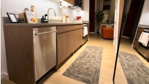 Une cuisine moderne avec des meubles en bois, des appareils en acier inoxydable et un grand îlot central. On y trouve également un coin repas avec un canapé et un tapis.
