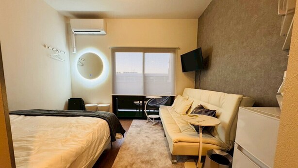 A hotel room with a bed, a sofa, a small table, a TV, and a window with a view. - New! LuxurySweet Hakata Ekiminami 52 ・Max 3~4 people, 5 min. drive from Hakata Station, New construction (Fukuoka Hakata Ward)