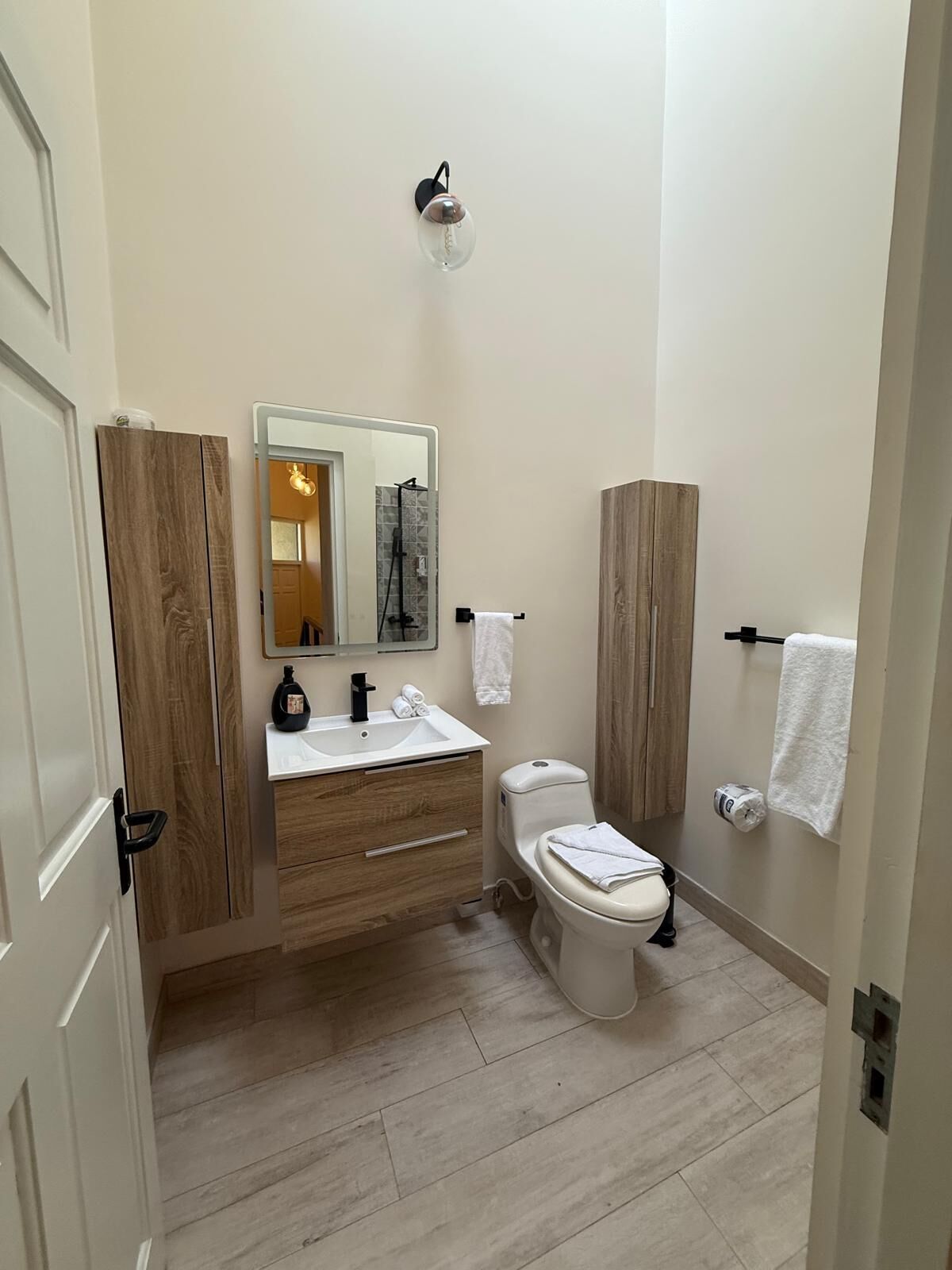 A modern bathroom with a wooden vanity, a toilet, and a shower area.