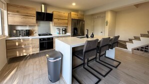 A modern kitchen with wooden cabinets, a stainless steel refrigerator, and a central island with bar stools. - Luxury Townhouse 6 Minutes from Beach & Casino (Oranjestad)