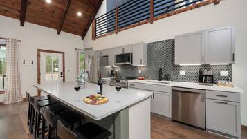 A modern kitchen with a large island, stainless steel appliances, and a herringbone tile backsplash.