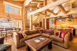 A log cabin interior with a wooden staircase, a dining area, and a living room furnished with sofas and a coffee table. - Experience luxury at Deer Valley Pine Inn 4, a ski-in/ski-out townhome in Park City. (Park City)