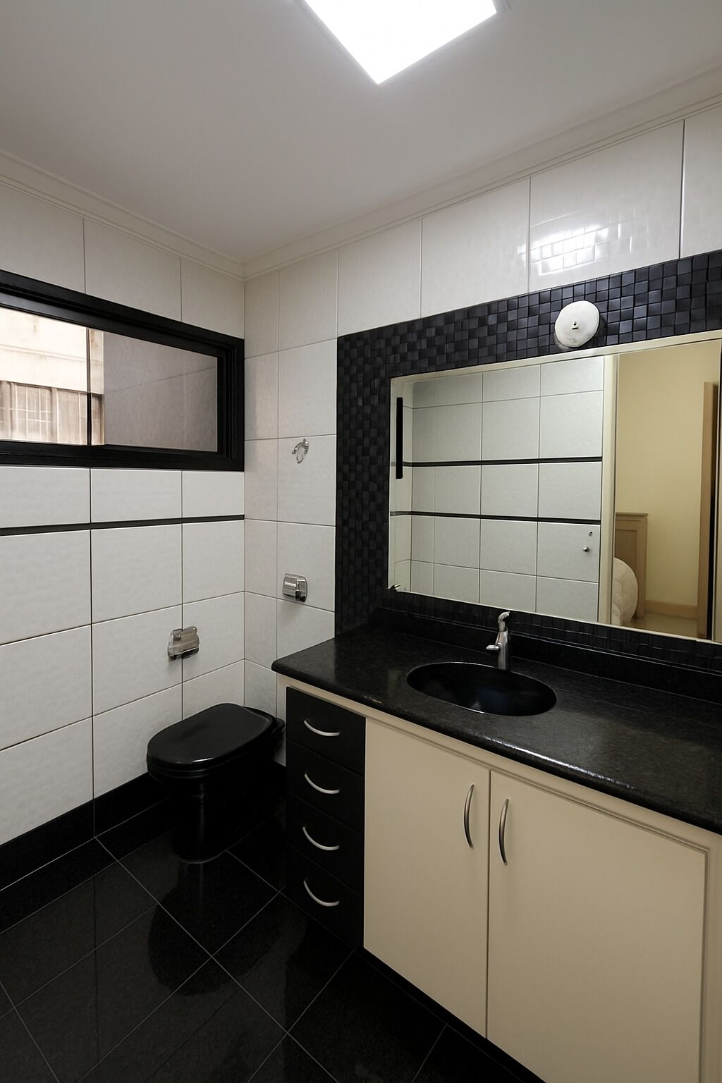 A modern bathroom with a black sink, white cabinets, and a large mirror.