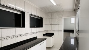 Cozinha moderna com armários brancos, bancadas pretas e piso ladrilhado.