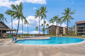 A swimming pool with palm trees, a building with balconies, and a clear sky. - SUMMER SALE! Ocean view 2BR condo in West Maui, perfect for groups of 6- PK L106 (Lahaina)