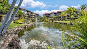 Un hotel con estanque de carpas koi, palmeras y cielo despejado.