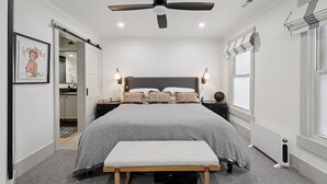 Ein Schlafzimmer mit einem großen Bett, Nachttischen, einem Deckenventilator und einer Bank.