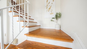 A wooden staircase with white railings and a white vase with a plant on the landing.