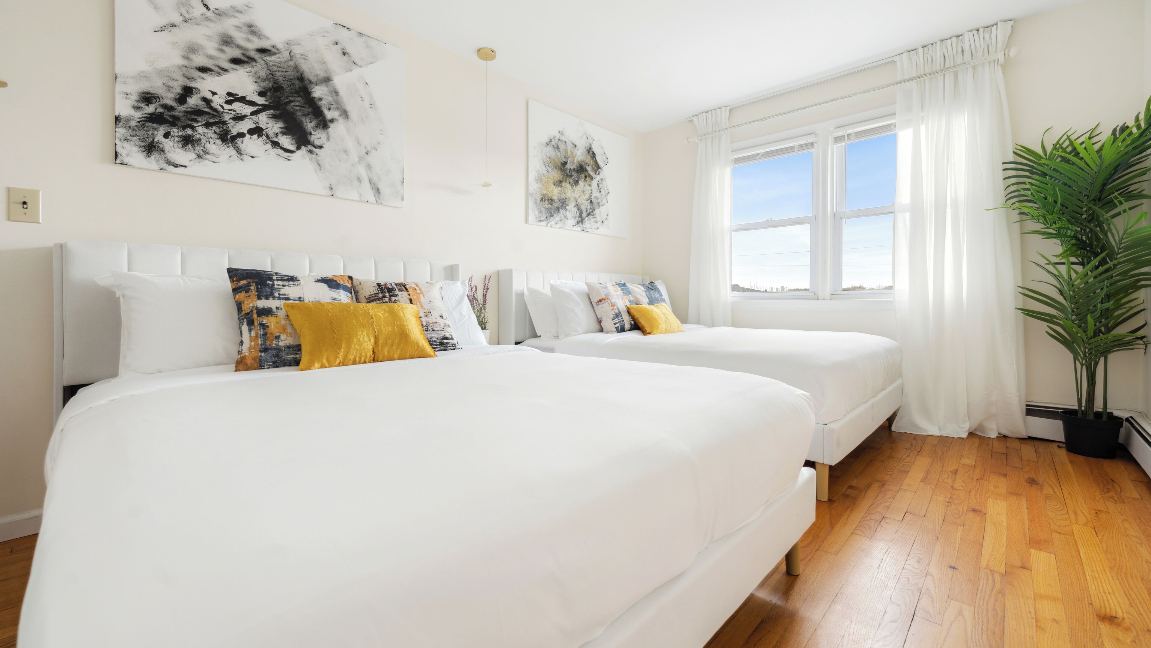 Habitación de hotel con dos camas, ropa de cama blanca y un ventanal con cortinas.