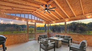 A covered outdoor patio with a ceiling fan, string lights, and a fire pit table surrounded by chairs. - 3-bedroom Rustic Retreat in Coushatta (Coushatta)