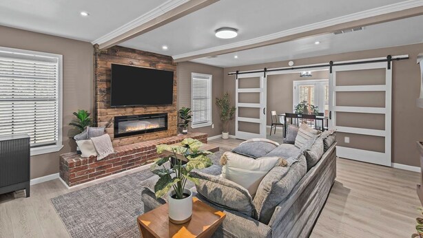 A living room with a fireplace, a large flat-screen TV, a sofa, and a sliding door closet. - 3-bedroom Rustic Retreat in Coushatta (Coushatta)