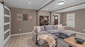 A modern living room with a sectional sofa, a wooden coffee table, and a built-in shelving unit. - 3-bedroom Rustic Retreat in Coushatta (Coushatta)