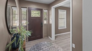A hallway with a brown door, a potted plant, and a round rug. - 3-bedroom Rustic Retreat in Coushatta (Coushatta)