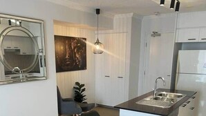 A modern kitchen with a glass island, a round mirror, and a pendant light. - 2-bedroom Apartment 7 km from Brisbane Airport (Chermside West)