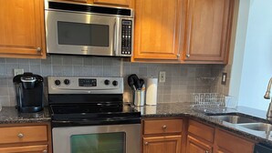 Een moderne keuken met houten kastjes, roestvrijstalen apparatuur en een granieten aanrecht.
